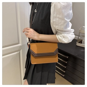 Detailed shot of a vintage-style brown crossbody bag worn by a model in casual attire