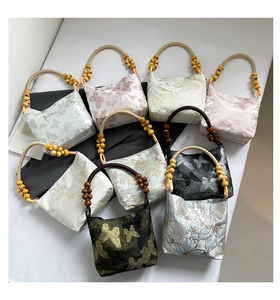 Detail of silk brocade fabric patterns and wooden bead handles on ethnic tote bags