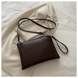Detail of minimalist dark brown leather tote bag with adjustable strap and metal hardware