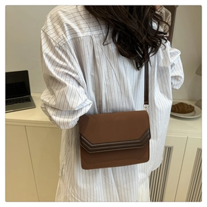Detail view of a brown rectangular crossbody bag styled with a striped shirt