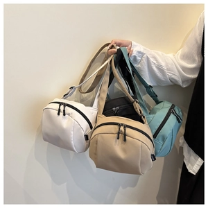 Detail of multi-color nylon crossbody bags featuring a curved zipper and adjustable strap