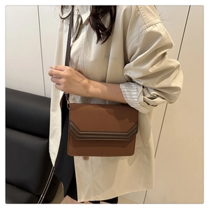 Close-up of brown crossbody bag with V-shaped quilted design on a fashion model