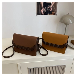 Detail of trendy suede patchwork envelope crossbody bags in brown and ginger yellow