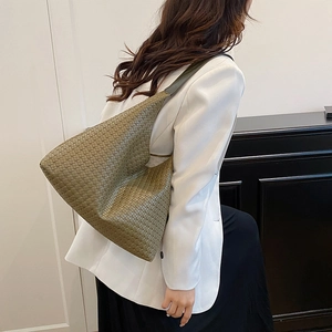 Olive green woven hobo tote bag shown with a chic white blazer and black skirt outfit