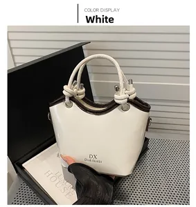 Detail der weißen Beuteltasche mit braunen Kanten und geknotetem Griff-Design