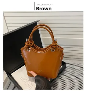 Detail einer braunen Eimer-Tasche aus Leder mit geknotetem Schultergurt und Metall-Details