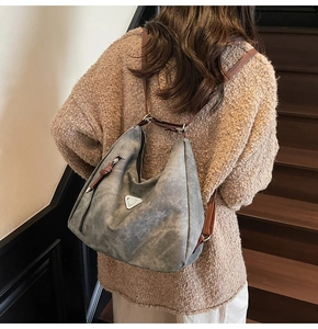 Detail view of large blue contrast tote bag with silver triangle hardware and leather strap