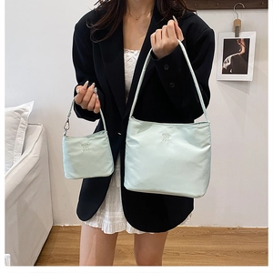 Dettaglio borsa a secchiello in nylon menta con scritta ENJOY THE LIFE a rilievo e mini pochette