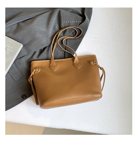 Detail view of the tan leather tote bag with side metal eyelet and drawstring accents