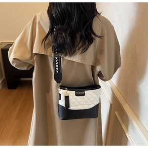 Detail of quilted crossbody bag featuring monochrome color blocking and patterned wide strap