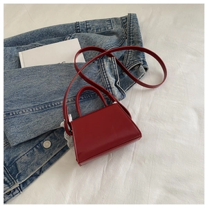 Detail shot of a red mini trapezoid handbag with lace lining on a denim background