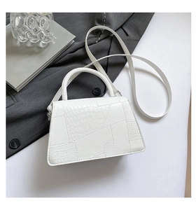 Detailed view of white crocodile pattern small square bag with textured handle and strap