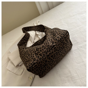 Détail du sac fourre-tout vintage en toile léopard sur fond de blazer blanc