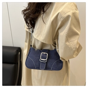 Détail du sac en denim bleu foncé avec grande boucle argentée et surpiqûres blanches