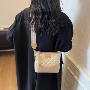 Beige quilted crossbody bag with stylish wide woven strap and minimalist design