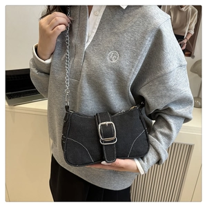 Détail du sac bandoulière en denim noir avec chaîne argentée et grande boucle carrée