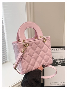 Detailed macro shot of pink quilted stitching and gold ring hardware on a handbag