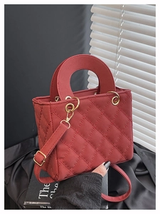Detail of red quilted leather handbag with gold hardware and removable shoulder strap