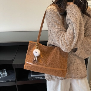 Leopard print suede tote bag for women with plush doll charm shown in lifestyle setting