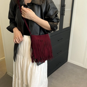 Sac bandoulière en daim bordeaux avec de longues franges, porté par un mannequin chic