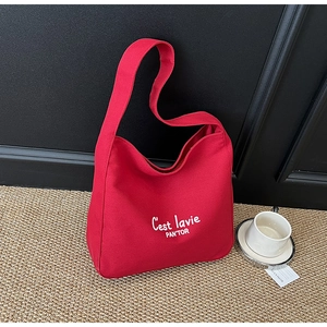 Gros plan d'un sac hobo en toile rouge avec lettrage C'est la vie blanc sur un tapis