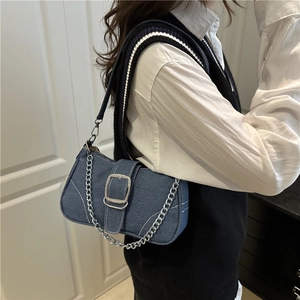 Sac baguette en denim bleu vintage avec chaîne argentée porté par un mannequin