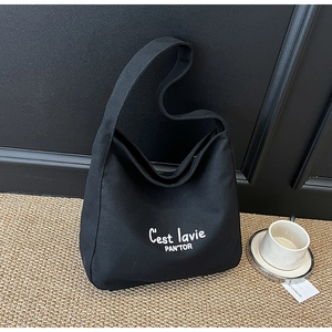Détail du sac hobo en toile noire avec inscription C'est lavie blanche et bandoulière robuste
