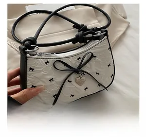 Dettaglio del tessuto seersucker bianco con stampa fiocco nero e ciondolo a cuore
