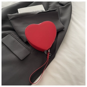 Dettaglio della pochette rossa a forma di cuore con elegante cinturino e cerniera lampo