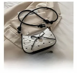 Dettaglio della borsa sottobraccio in pelle pieghettata bianca con fiocchi e cuore