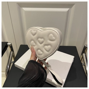 Dettaglio della borsa a cuore crema in pelle PU con cuciture a rilievo e cinturino a mano