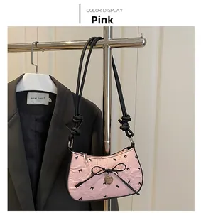 Borsa a mezzaluna rosa plissettata con motivi a fiocco nero e ciondolo a cuore