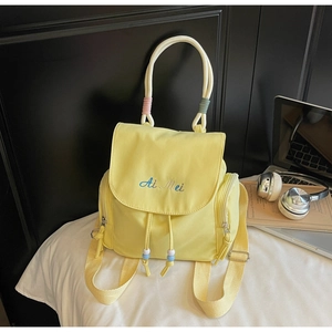 Detail of light yellow backpack with letter embroidery and durable fabric handle