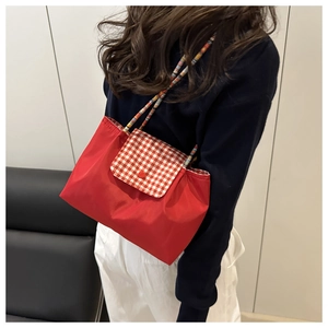 Détail du cabas en nylon rouge avec rabat à carreaux et bandoulière en corde tressée