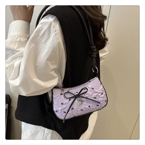 Detail of lavender pleated underarm bag with black bow patterns and heart pendant