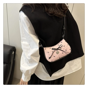 Sac sous le bras rose avec motifs nœuds noirs et pendentif cœur sur modèle