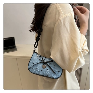 Détail du sac sous l'aisselle bleu clair à imprimé nœuds avec bandoulière et pendentif