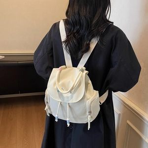 White minimalist canvas backpack with blue letter embroidery and decorative drawstring