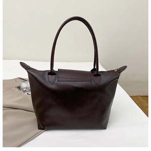 Detailed macro view of dark burgundy glossy PU leather tote bag with elegant gold zipper