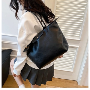 Side view of large black PU leather tote bag with long straps and gold buckle detail