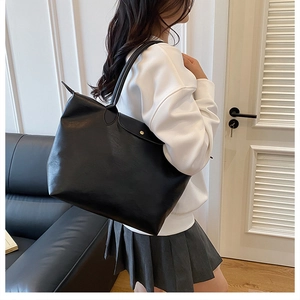 Detail of a black faux leather tote bag with flap closure and metallic button for women