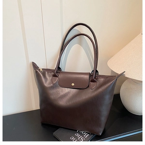 Detail of coffee brown leather tote bag showing high-quality texture and folding flap design