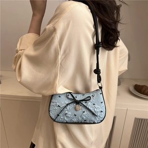 Sac sous le bras en jacquard bleu avec nœud noir, pendentif cœur et bandoulière texture