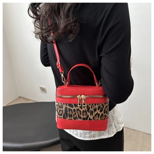 Detailed view of red leopard print bucket bag crossbody style worn by model for scale