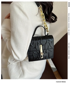 Detail of embossed black PU leather crossbody bag with chunky gold chain strap
