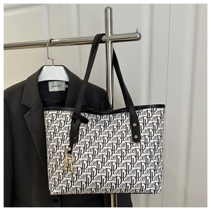 Détail d'un sac cabas vintage avec motif monogramme et pendentif en métal doré