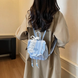 Blue plaid mini backpack with lace bow and ruffle detail on khaki trench coat