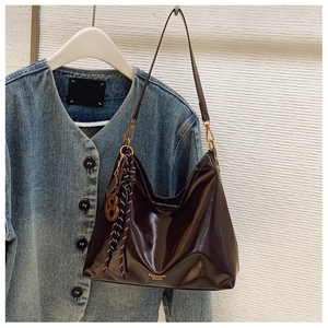 Detail of dark brown glossy patent leather hobo bag with gold hardware and silk scarf