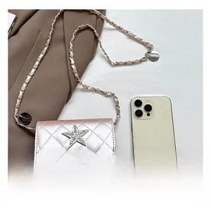 Mini borsa trapuntata con catena e stella di strass rispetto a uno smartphone