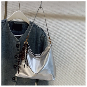 Detail of silver metallic hobo bag featuring a decorative silk scarf and gold logo